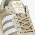 Le modèle présenté dans l'image est la adidas ZX 700 HD dans son coloris bleu marine classique avec les trois bandes blanches caractéristiques de la marque adidas.