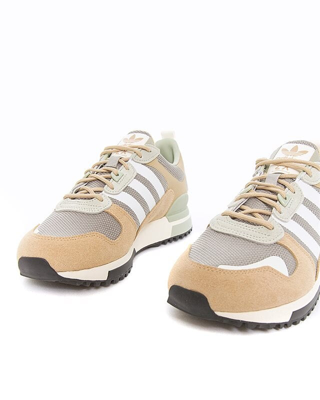 Le modèle présenté dans l'image est la adidas ZX 700 HD dans son coloris bleu marine classique avec les trois bandes blanches caractéristiques de la marque adidas.