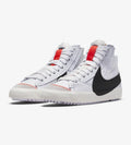 Nike Blazer Mid '77 Jumbo sont caractérisées par un grand logo Swoosh noir sur le côté et une languette orange vif.