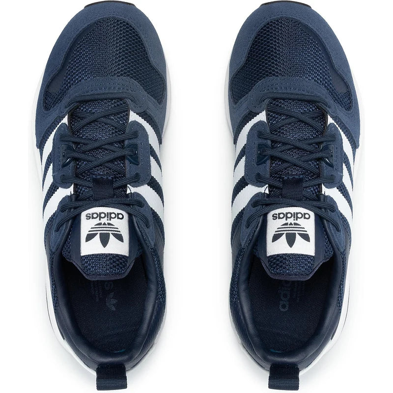 Le modèle présenté dans l'image est la adidas ZX 700 HD dans son coloris bleu marine classique avec les trois bandes blanches caractéristiques de la marque adidas.