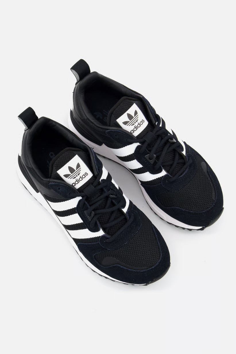 Le modèle présenté dans l'image est la adidas ZX 700 HD dans son coloris bleu marine classique avec les trois bandes blanches caractéristiques de la marque adidas.